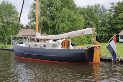 zeiljol aangemeerd langs groene oever