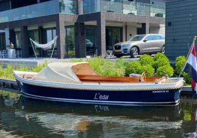 blauwe sloep aan kade met woning op achtergrond