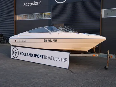 witte sportboot op trailer voor bedrijfspand