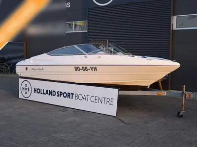 witte sportboot op trailer voor bedrijfspand