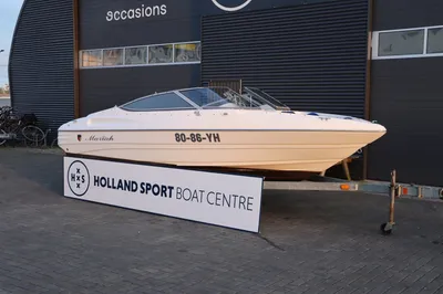 witte sportboot op trailer voor bedrijfspand