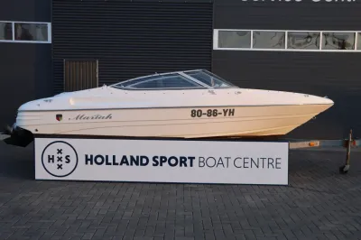 witte sportboot op trailer voor gebouw
