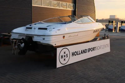 witte motorboot op trailer bij bedrijfspand
