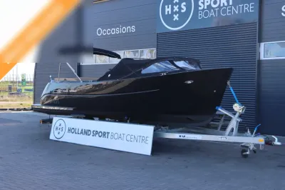 zwarte tender op trailer bij bedrijfsgebouw