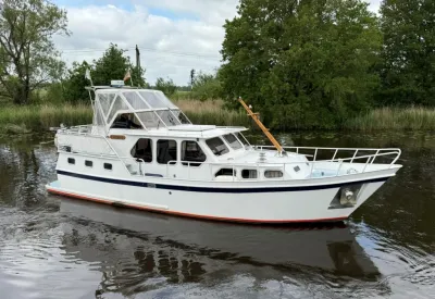 wit motorjacht op binnenwater bij groene oever