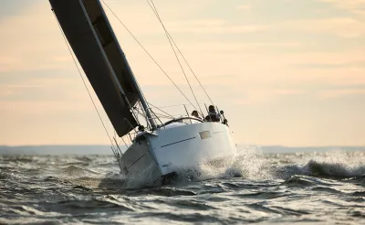 zeilboot in ruwe zee bij avondlicht