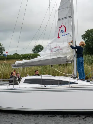 zeilboot met bemanning en opgehesen zeil