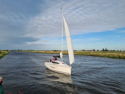 zeilboot op rivier met grasoevers