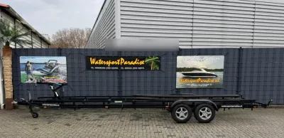 tandemasser trailer naast hek met reclameborden
