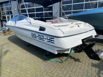 wit bowrider op parkeerplaats bij loods