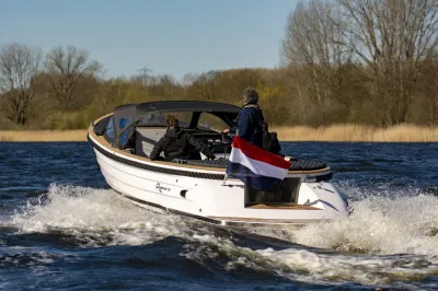 tender op water met personen en Nederlandse vlag