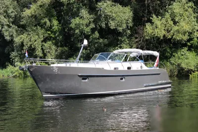 motorjacht op rivier bij beboste oever