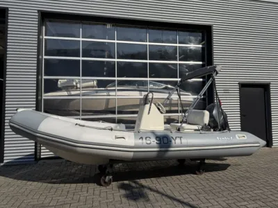 grijze rib met buitenboordmotor bij bedrijfsdeur