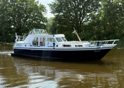 witte kruiser op rivier met boombegroeiing