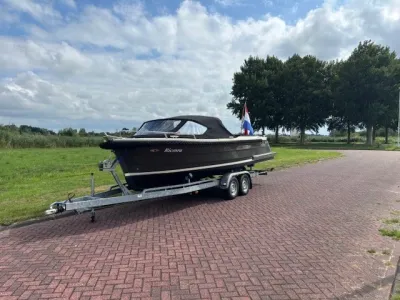 sloep op trailer naast gras en bomen