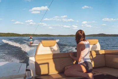vrouw zittend op boot kijkt naar wakeboarder