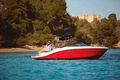 rood-witte speedboot met personen bij kust