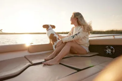 Vrouw en hond zittend op voorschip bij zonsondergang