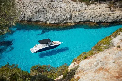 boot in helder turquoise water bij rotsen