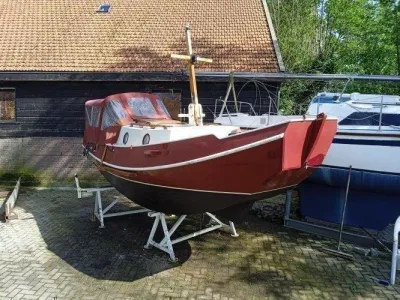rood houten boot op bokken naast loods