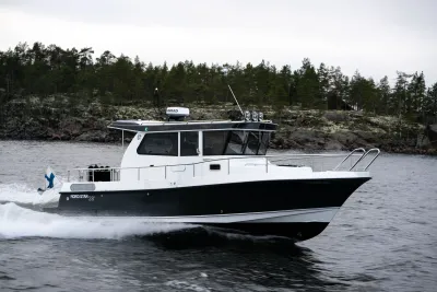 varend motorjacht bij beboste kust