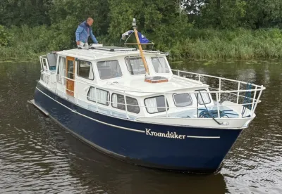 motorkruiser op binnenwater bij boomrijke oever