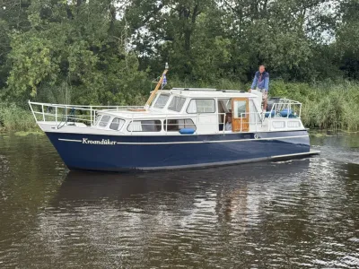 motorkruiser op kanaal bij begroeide oever