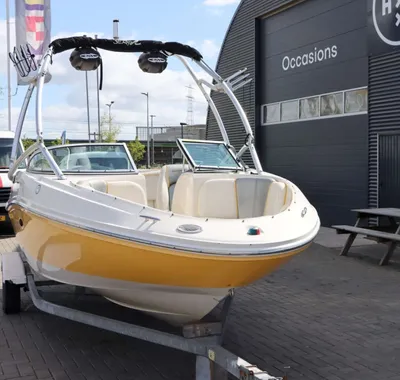 Gele witte speedboot op trailer bij bedrijfsgebouw