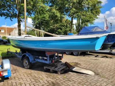 blauwe zeilboot op trailer op parkeerplaats