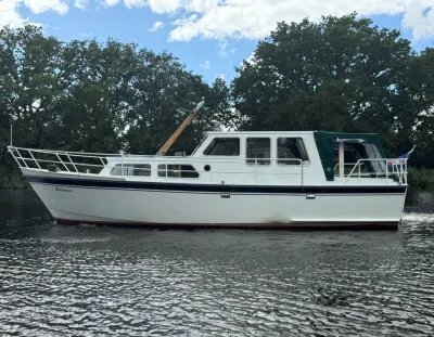 Wit motorjacht in het water langs bomen