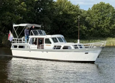 witte kruiser op rustig water bij bomen
