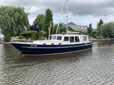 motorjacht in kanaal bij bomen en huizen