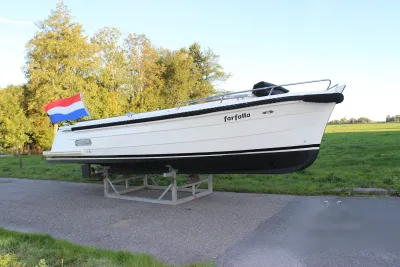 witte sloep op stelling langs grasland