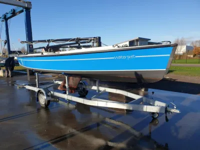 blauwe zeilboot op trailer bij water