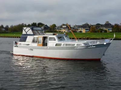 wit motorjacht op kanaal met huizen op oever