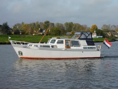wit motorjacht op rivier bij oever