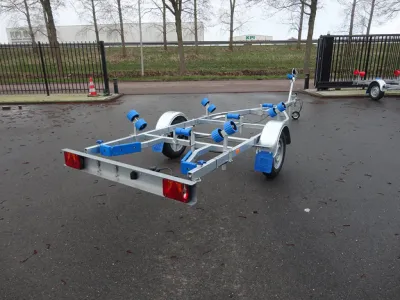 boottrailer op asfalt bij hek en bomen