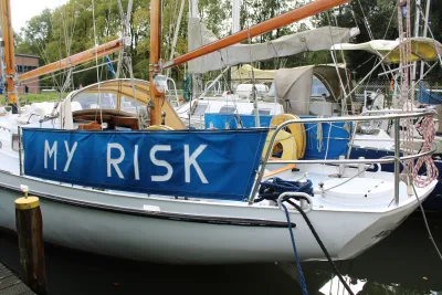 zeilboot afgemeerd met blauw scherm en touwen