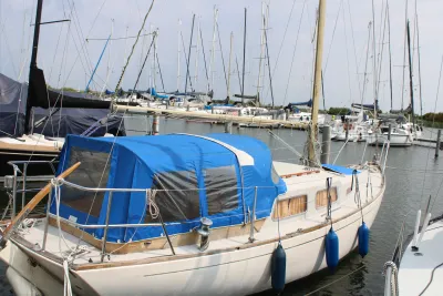 zeilboot met blauwe kuiptent in jachthaven