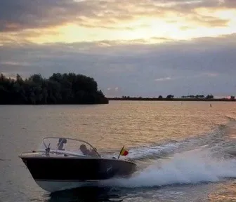 motorboot rijdend op water bij zonsondergang