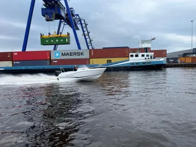snelboot varend in haven met containers
