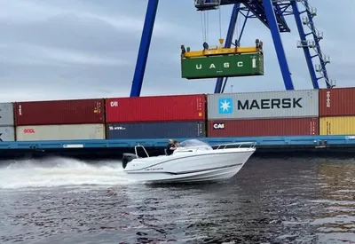 wit motorjacht varend langs containerkade