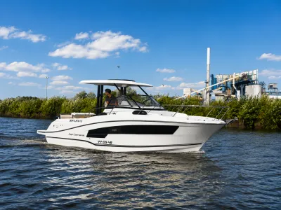 witte sportboot op water met industrie op de achtergrond