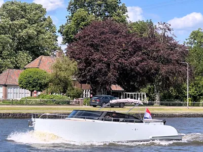 witte motorboot varend langs kade