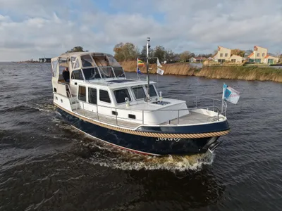 wit motorjacht op binnenwater nabij oever