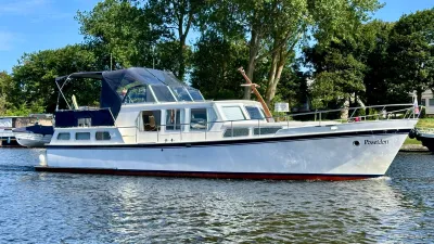 wit motorjacht op water bij beboomde kade
