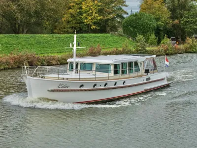 wit motorjacht varend op kanaal langs oever