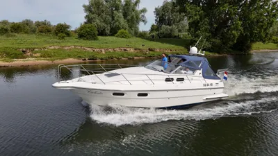 wit motorjacht varend langs groene oever