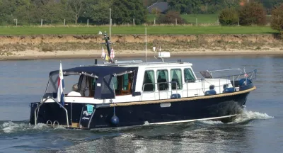 motorjacht op rivier met oever op de achtergrond