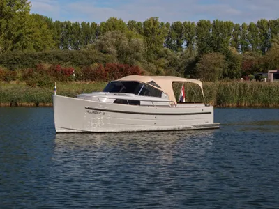 cabinsloep op rustig water bij groene oever